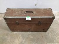 Closed railroad style old wooden toolbox with metal frame and handle on top.