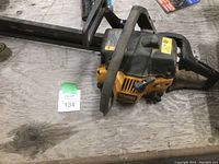 Top angle image showing full chainsaw with bar attached, placed on a wooden surface with lot tag visible.