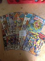Lot of 10 assorted DC Comics comic books fanned out on surface, titles visible including Doom Patrol, Star Squadron, The Outsiders, various conditions.