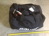Closed Bauer hockey bag with visible Bauer branding and some hockey gear inside.