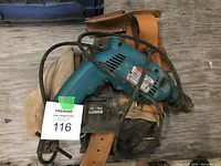 Makita blue-green corded electric drill with attached cord and leather tool belt.