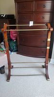 Full view of wooden blanket rack with two wooden cross rods and brass rods at base.