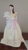 Front view of Coalport hand painted figurine "Tenderness" showing the white gown with floral designs and a pink scarf.