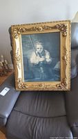 Front view of framed print showing boy holding fishing pole, ornate gold wood frame