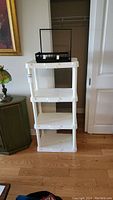 Full front view of white resin 4-level shelving unit.
