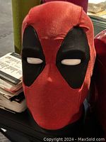 Deadpool talking head statue with red and black fabric covering and white eyes