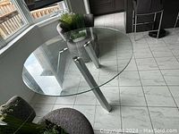 Round glass top table positioned near windows on white tile floor showing overall design