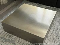 Front view of square brushed metal coffee table on patterned rug