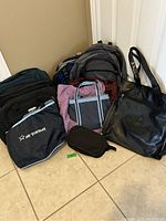 Photo showing 10 bags including backpacks, a small pouch, and a black Adidas leather tote bag with embossed logo, arranged on floor.