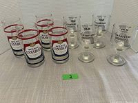 4 Molson Canadian beer glasses and 4 Niagara Falls wine glasses shown together on a table cloth.