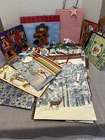 Overview photo showing multiple Christmas gift bags with various holiday designs such as nutcracker, snowflakes, deer, and festive stripes alongside curling ribbon and bows.