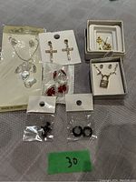 Overview of jewelry pieces in packaging and small boxes showing earrings and necklace chains.