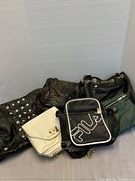 Photo showing six assorted purses in black, brown, white and green colors, arranged side by side with a white and black background.