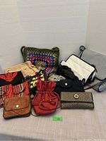 Photo showing 14 assorted purses, wallets, and bags arranged on a surface including crochet, fabric, leather, and quilted styles.