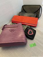 Lot of 4 purses, 1 bag, and 1 coin bag arranged with visible textures and shapes