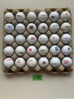 Top view of 30 used golf balls arranged in a cardboard holder showing various logos such as Canon, Citibank, and more.