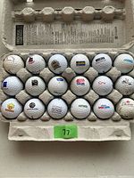 Photo showing all 18 golf balls in a cardboard holder, logos visible for identification including Castle, CN, Tim-BE, Genumark, Hershey Sport Zone, Canadian, and others.