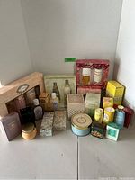 Wide view of lot showing about 25 items including boxed perfumes, lotions, and powders arranged on a white background