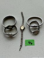 Photo of five vintage ladies wristwatches laid out on a white surface, with three watches grouped together and two more separated, showing various styles of metal bands and dial shapes.