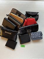 Overhead view of all 12 wallets showing variety of colors and styles including black, red, brown, and gray with star pattern.