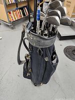 Peerless black golf bag with golf clubs inside and carrying strap visible in indoor room