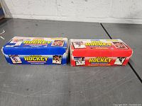 Two colorful rectangular boxes — one blue and one red — for 1990 Parkhurst Hockey Premier Edition Trading Cards, set on a grey surface.
