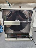 Full front view of Mitsubishi Interplay System X7 showing the large turntable behind the transparent cover and the control panel below.