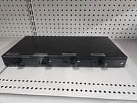 Photo of the full device on a pegboard shelf, showing top and front with four knobs and switches