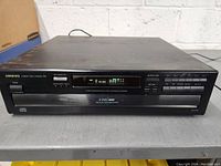 Front view of Onkyo 6 Disc Compact Disc Changer R1 showing digital display, buttons, and disc tray.
