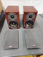 Pair of Onkyo bookshelf speakers with grills removed showing two drivers each (tweeter and midwoofer) and wood finish cabinet.