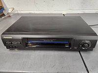 Front view of Panasonic VHS VCR showing brand, tape slot and control buttons.