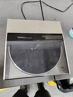 Closed turntable with dust cover showing the Technics SL-5 logo and direct drive automatic turntable system marking. Surface scratches are visible on the dust cover.