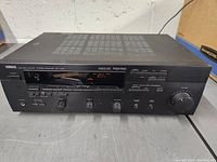 Front view showing the display panel, control knobs, Yamaha brand label, and input/output indicators.