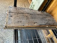 Close-up photo of rectangular barnboard piece showing weathered surface, nail holes, and dents.