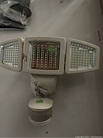 Front view of the motion sensor light showing three LED light panels and the central motion detection sensor in white plastic housing.