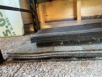 Stack of dark asphalt 3 tab shingles on concrete floor in barn