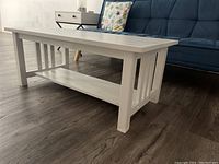 Angled view showing full top and side slatted panel with lower shelf under table top.