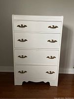 Front view of vintage white painted dresser with 4 drawers and brass handles