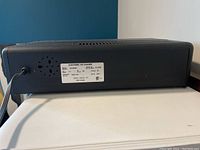 Black electronic air cleaner unit showing rear label with technical and model information.