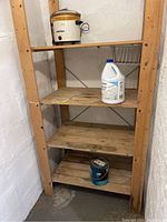 Pine shelving unit with four shelves and various household items placed on the shelves.