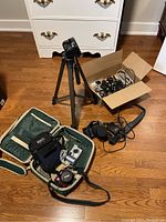 Photo of entire lot including tripod, two camera bags, assorted chargers and 3 digital cameras