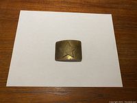 Front view of brass-tone belt buckle with raised Soviet star emblem on white background.