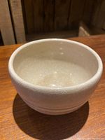 Side perspective of the cream tone tea bowl showing the mild sparkle glaze and overall shape.