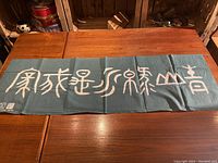 Full view of the green tenugui towel laid flat on a wooden surface showing the white Japanese characters.