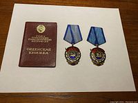 Red leather award booklet next to two medals front view