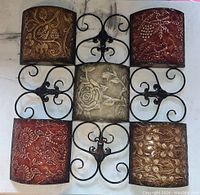 Metal wall decor with five embossed tin panels featuring floral and bird designs in a wrought iron scroll frame.