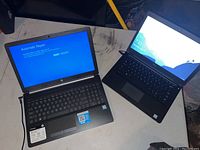 HP and Dell laptops on table, both plugged in, HP showing automatic repair screen