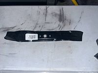 Two black metal lawn mower blades laid flat on a white surface, showing star-shaped mounting holes and label 561531B 2 Blade Set.