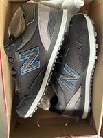 Side view of the black and grey New Balance running shoes with blue 'N' logo, showing upper material and design details