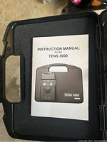 Instruction manual for the TENS 3000 showing device image on the cover inside the carrying case.